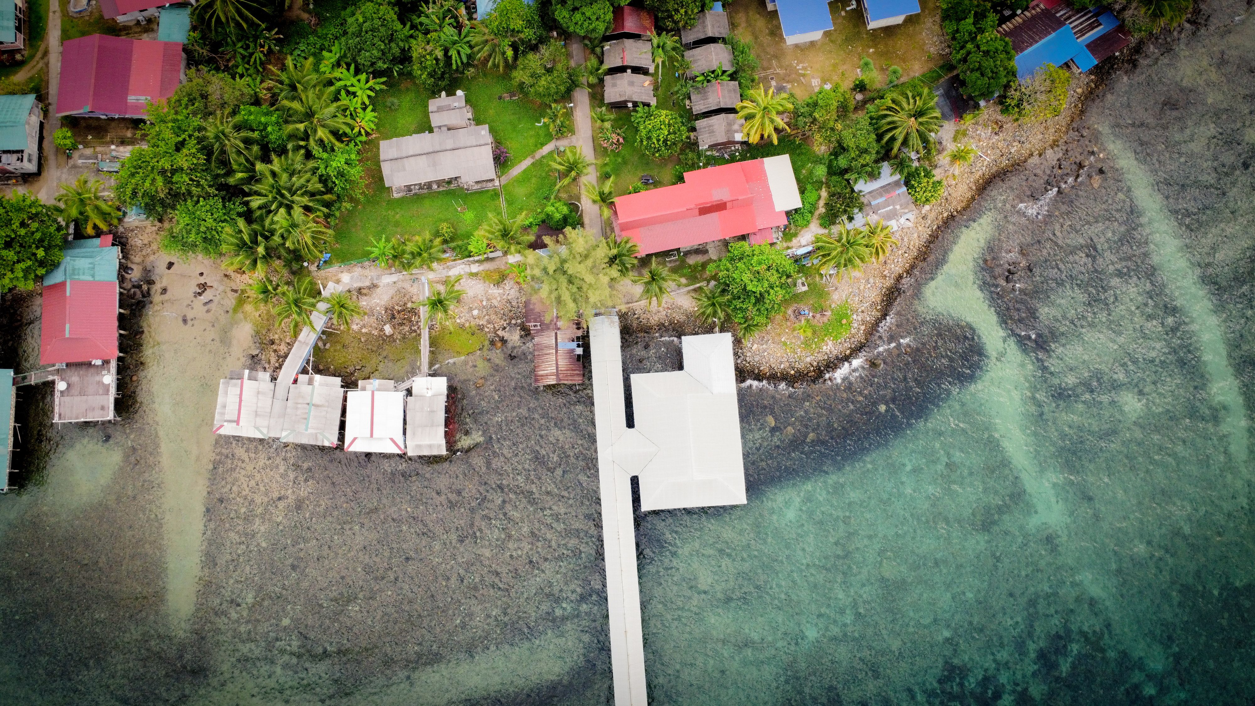 A scenic aerial shot of a tropical coastal village with vibrant houses and lush greenery.