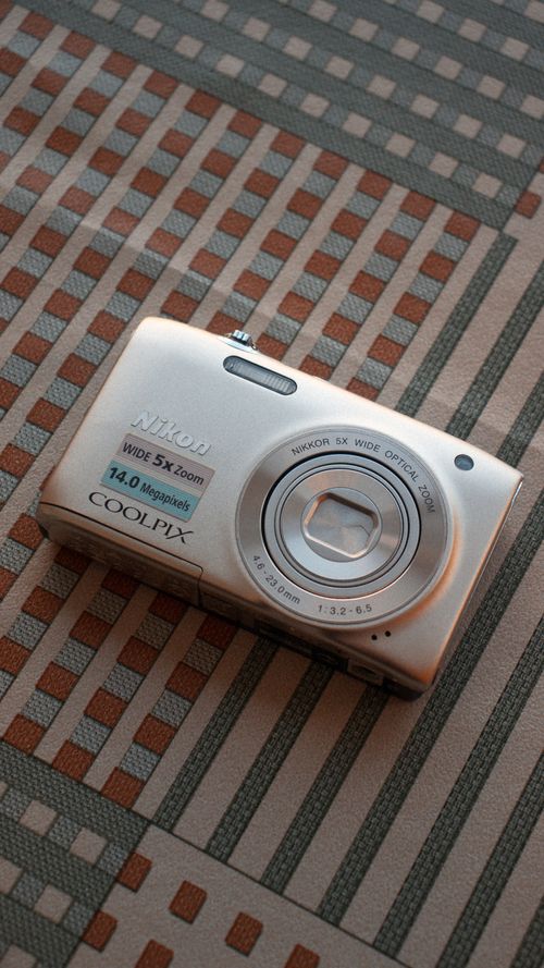 Free A vintage digital camera rests on a geometric patterned surface, capturing nostalgia and technology. Stock Photo