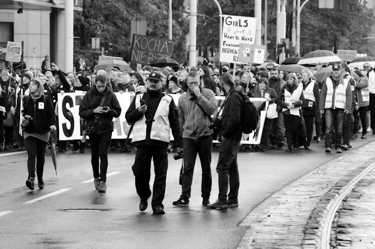 People With Posters Walking On Demonstration On City Street