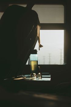 A serene train journey with a backpack, bottle, and eyeglasses illuminated by sunrise light through the window.