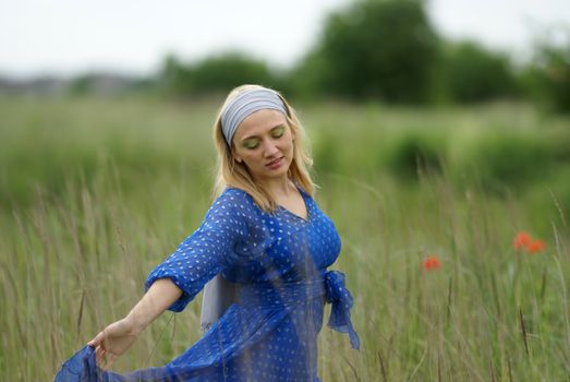 A Woman in a Blue Dress Dancing in a Field