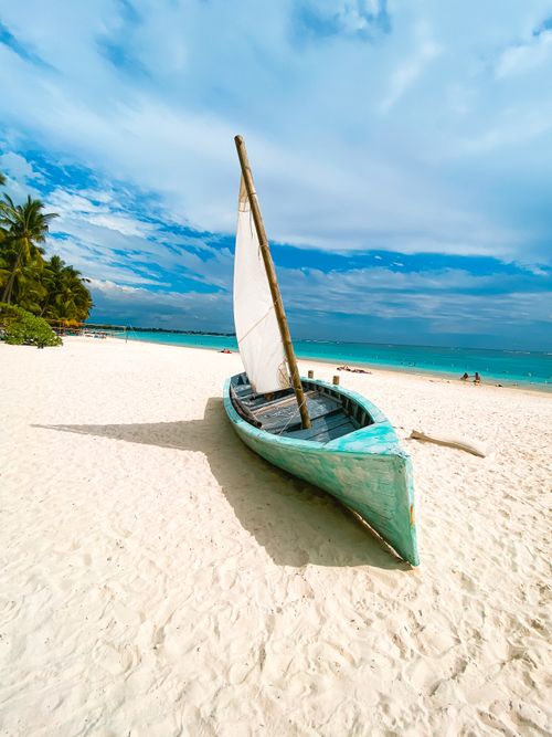 Free A picturesque traditional boat resting on the sandy Trou-aux-Biches beach under a clear blue sky in Mauritius. Stock Photo