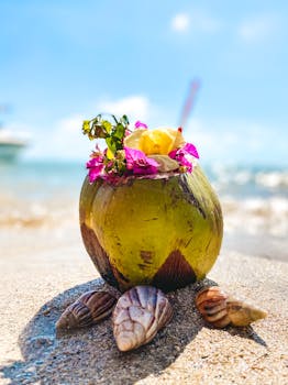 Vibrant coconut drink with flowers on sandy beach in Mauritius, ideal for tropical themes.