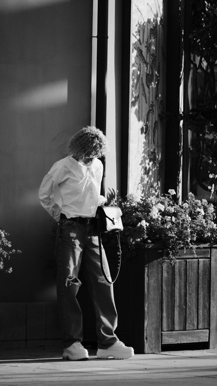 Fashion-forward woman poses on a sunny street corner, blending rustic elements with urban style.