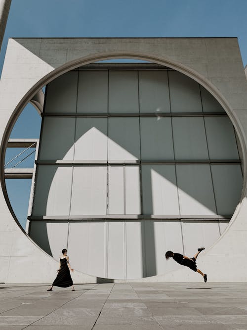 A Man and Woman Dancing in front of a Modern Building in City 