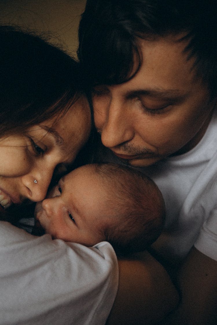 Mother And Father Embracing Little Baby