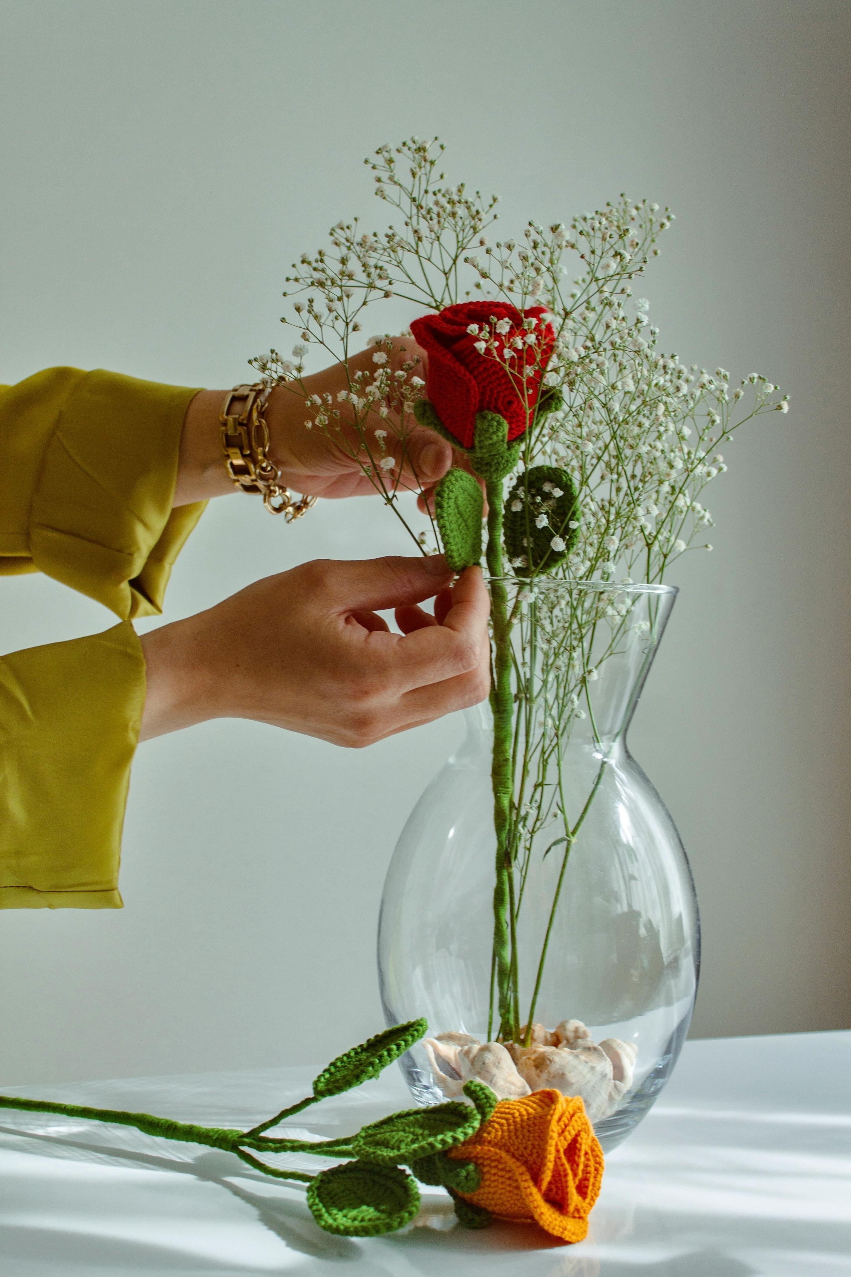 Mujer colocando flores de crochet en un jarrón - Foto de stock