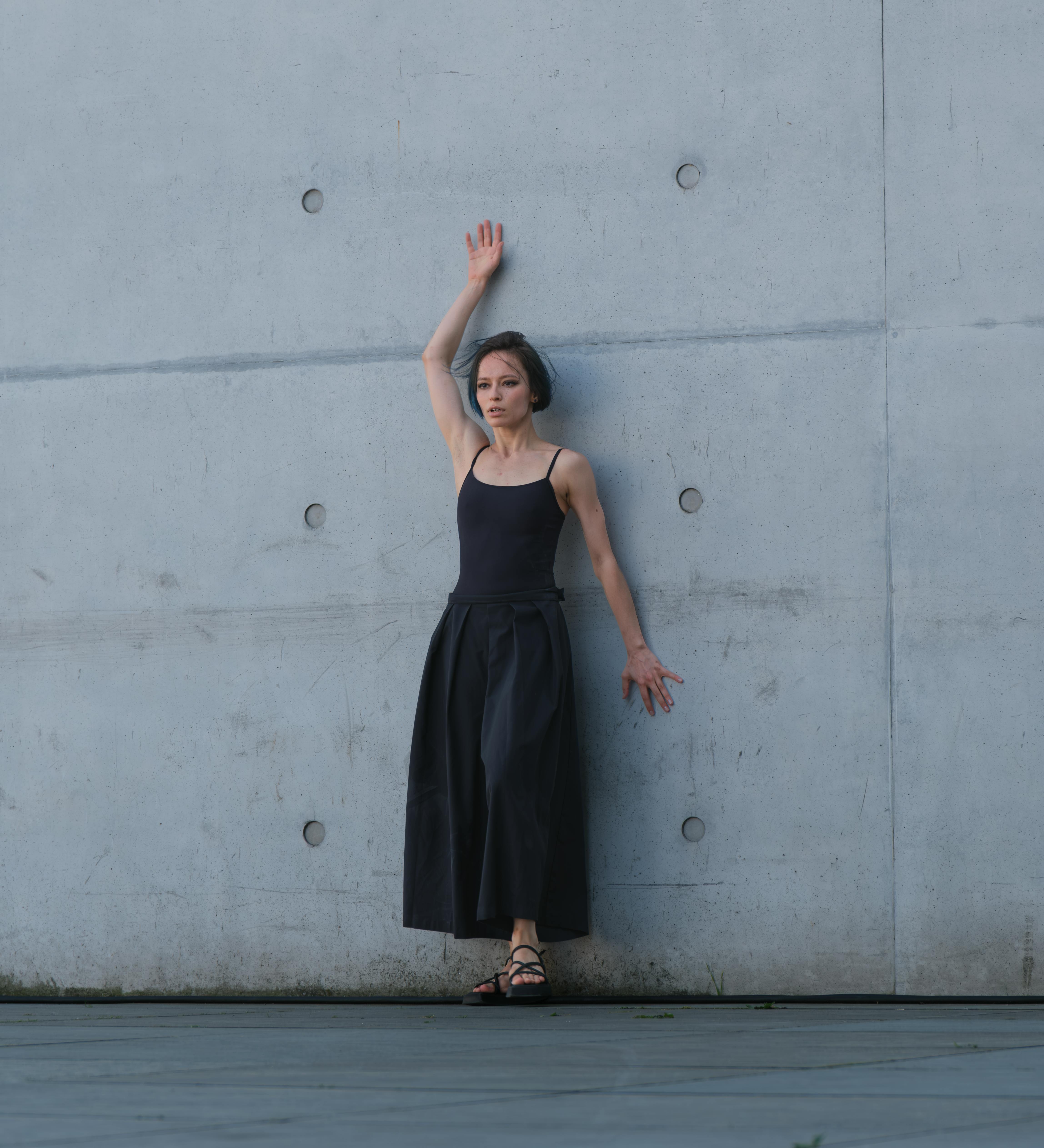 Woman in fashion outfit posing against a concrete wall in Berlin.