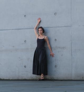 Woman in fashion outfit posing against a concrete wall in Berlin.