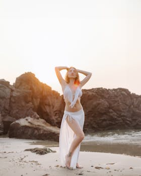 Elegant model posing on a beach at sunrise, perfect for fashion photography.