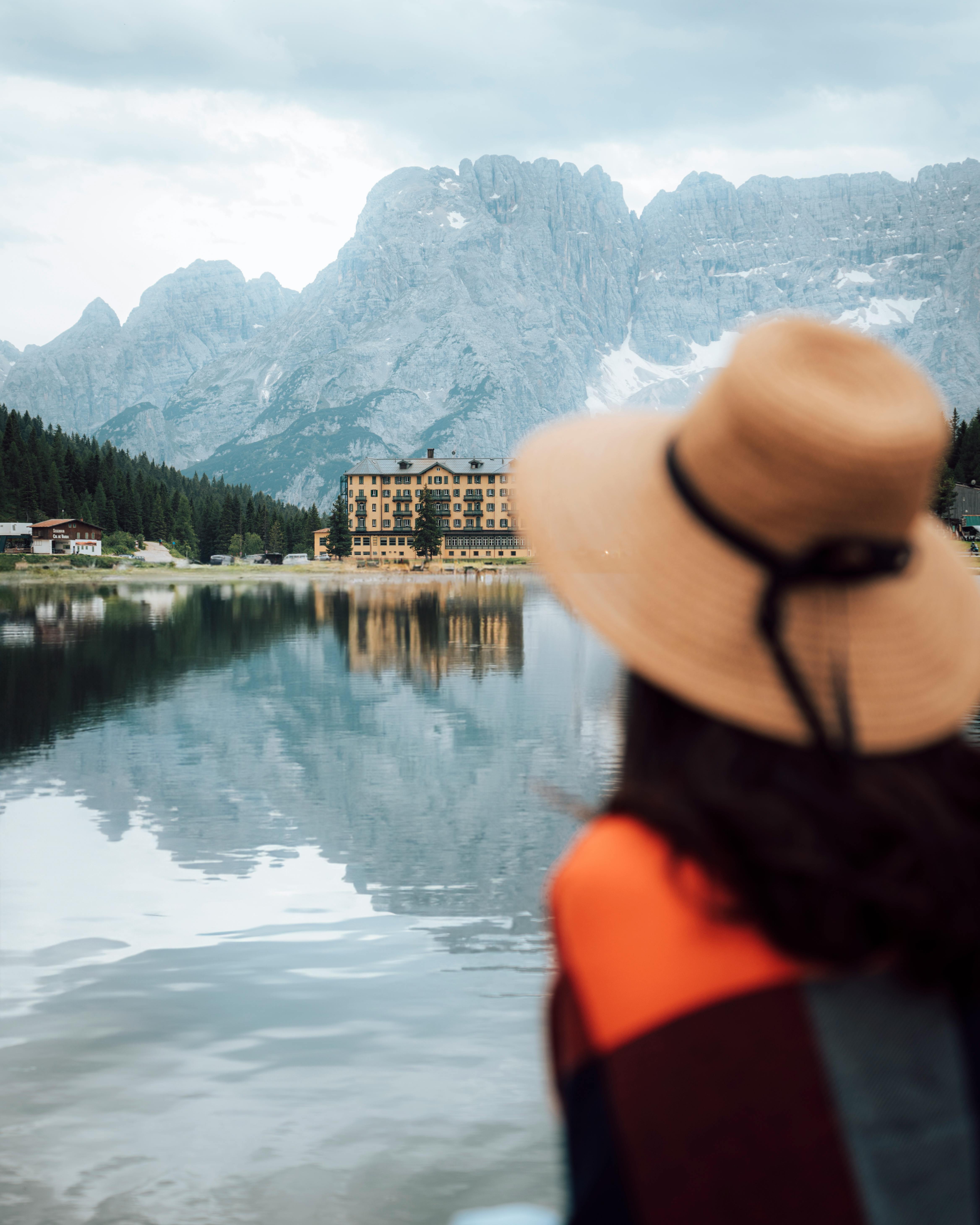 Woman admiring the serene mountain and lake view in Belluno, Italy.