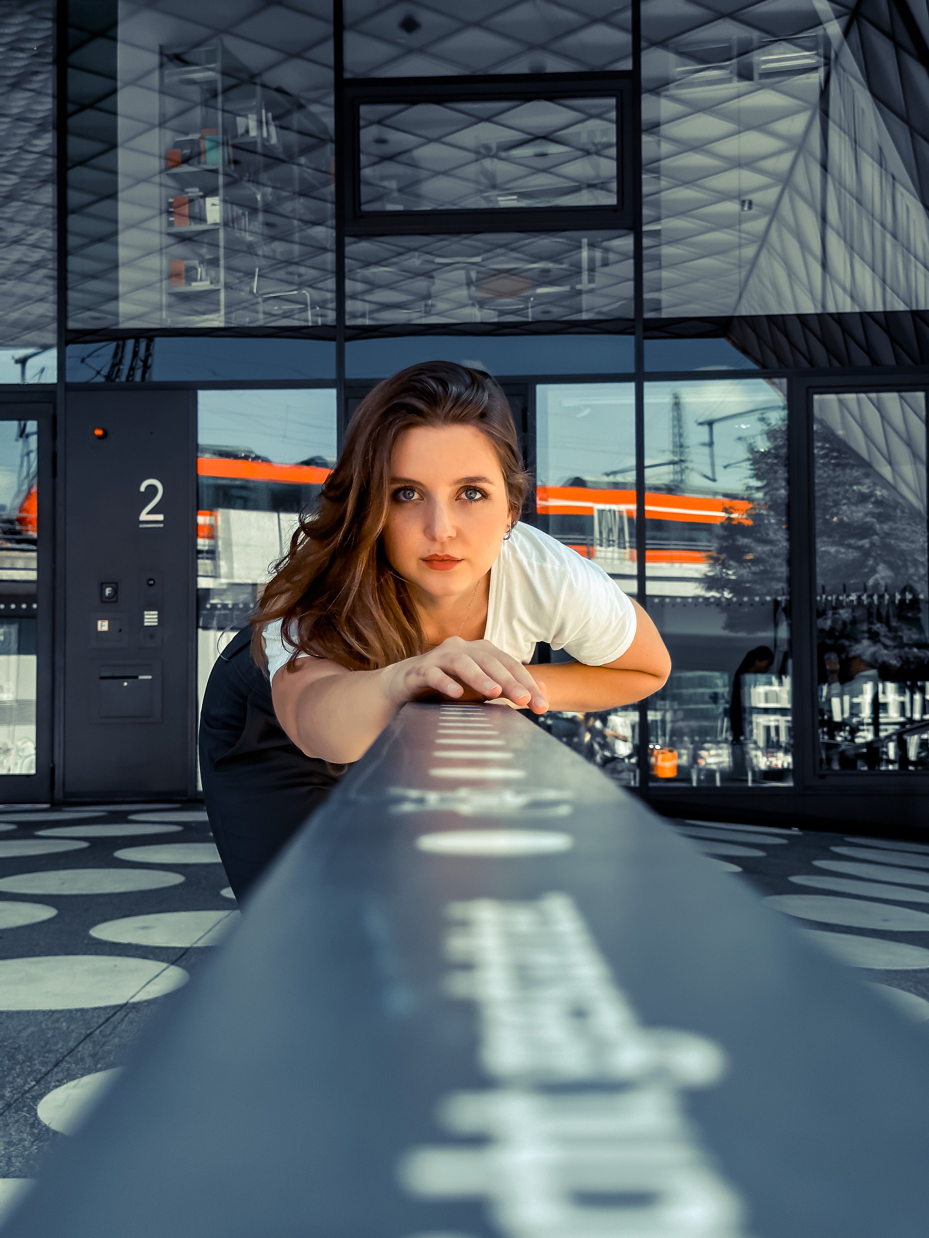 Creative portrait of a woman leaning forward against modern Berlin architecture.
