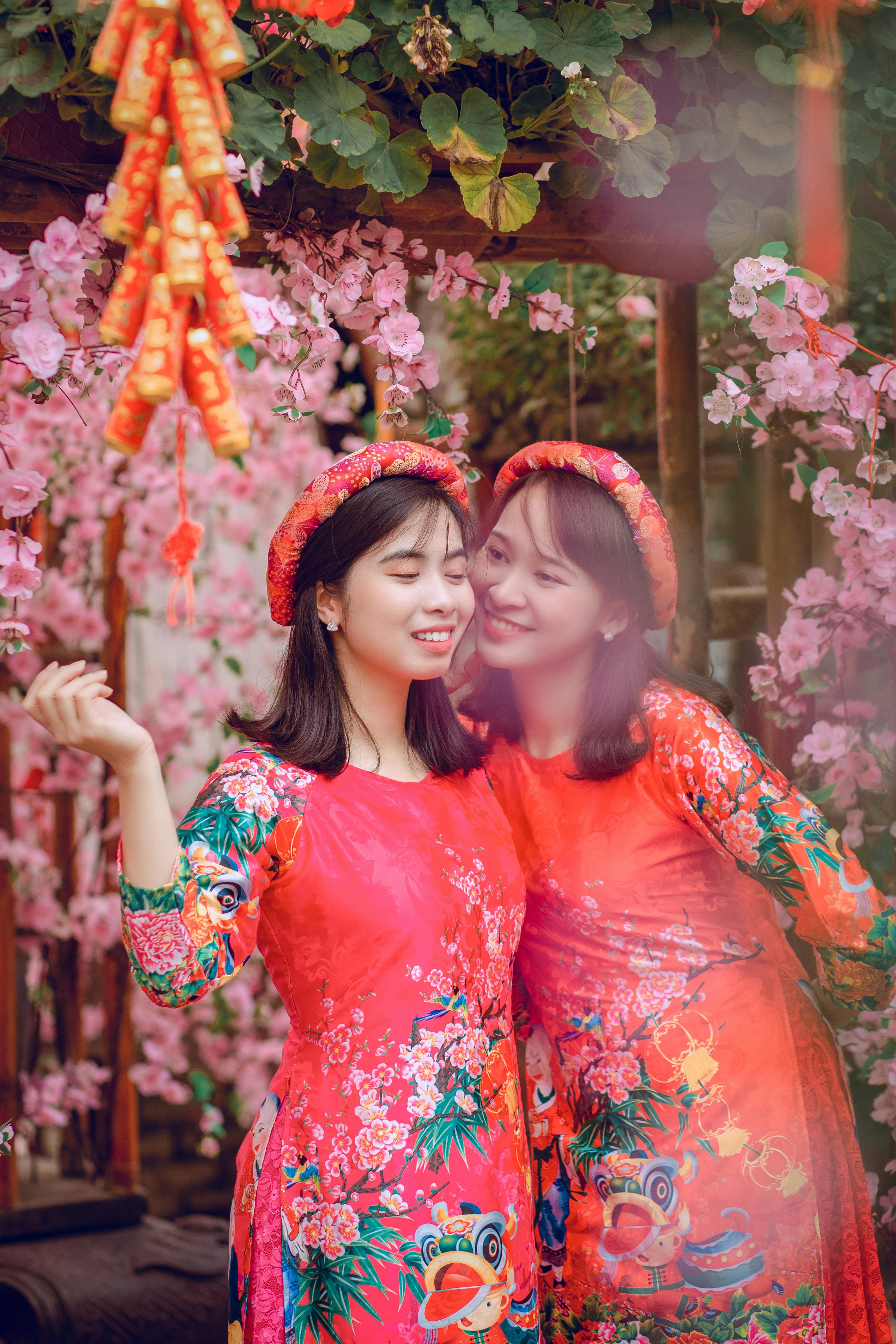 两名女性身着充满活力的越南传统服装，在花丛中庆祝文化