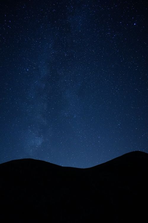 Free A breathtaking view of a star-filled night sky above silhouetted mountains, perfect for stargazing enthusiasts. Stock Photo