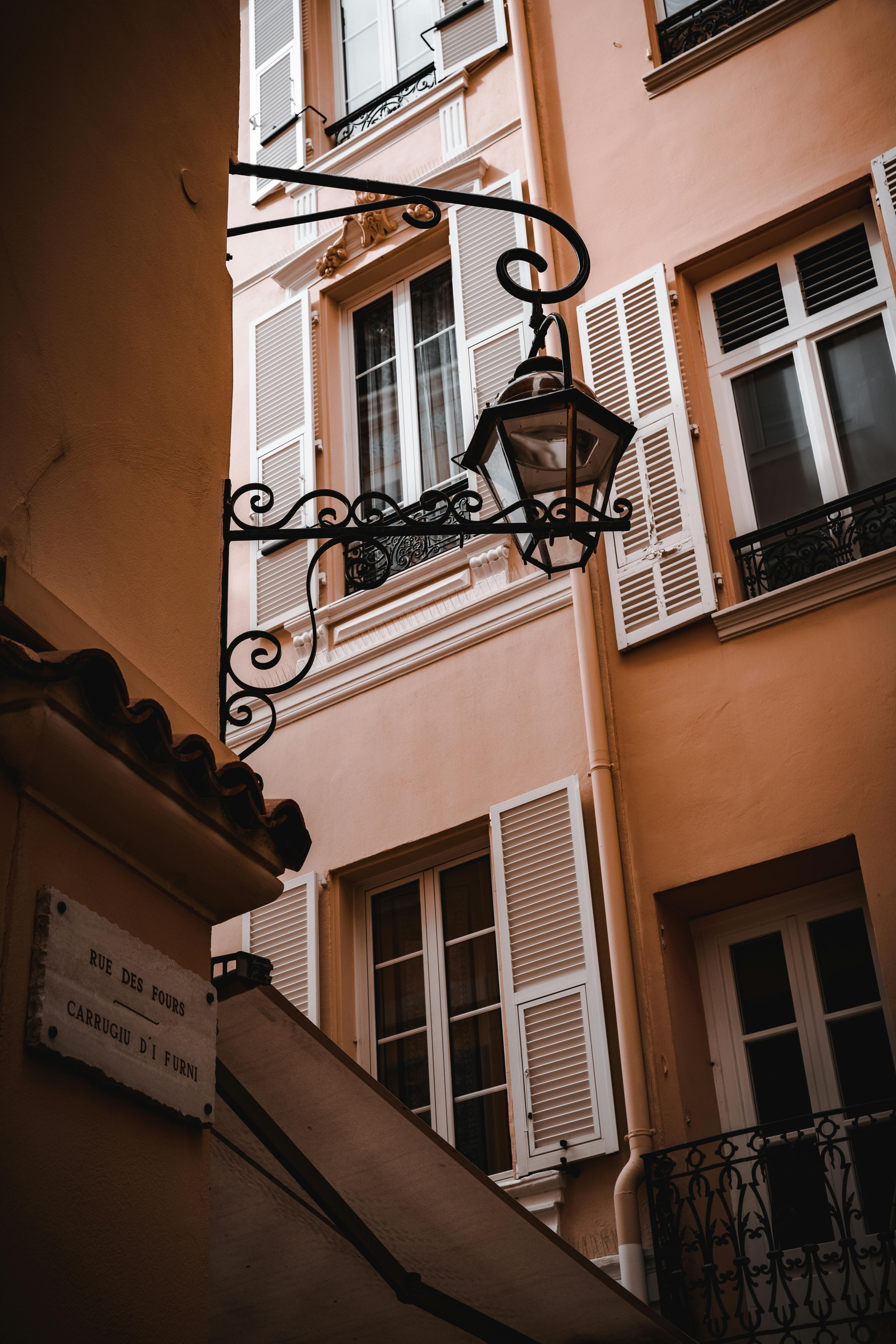 Elegant urban facade with vintage lamp and rustic shutters in warm tones.