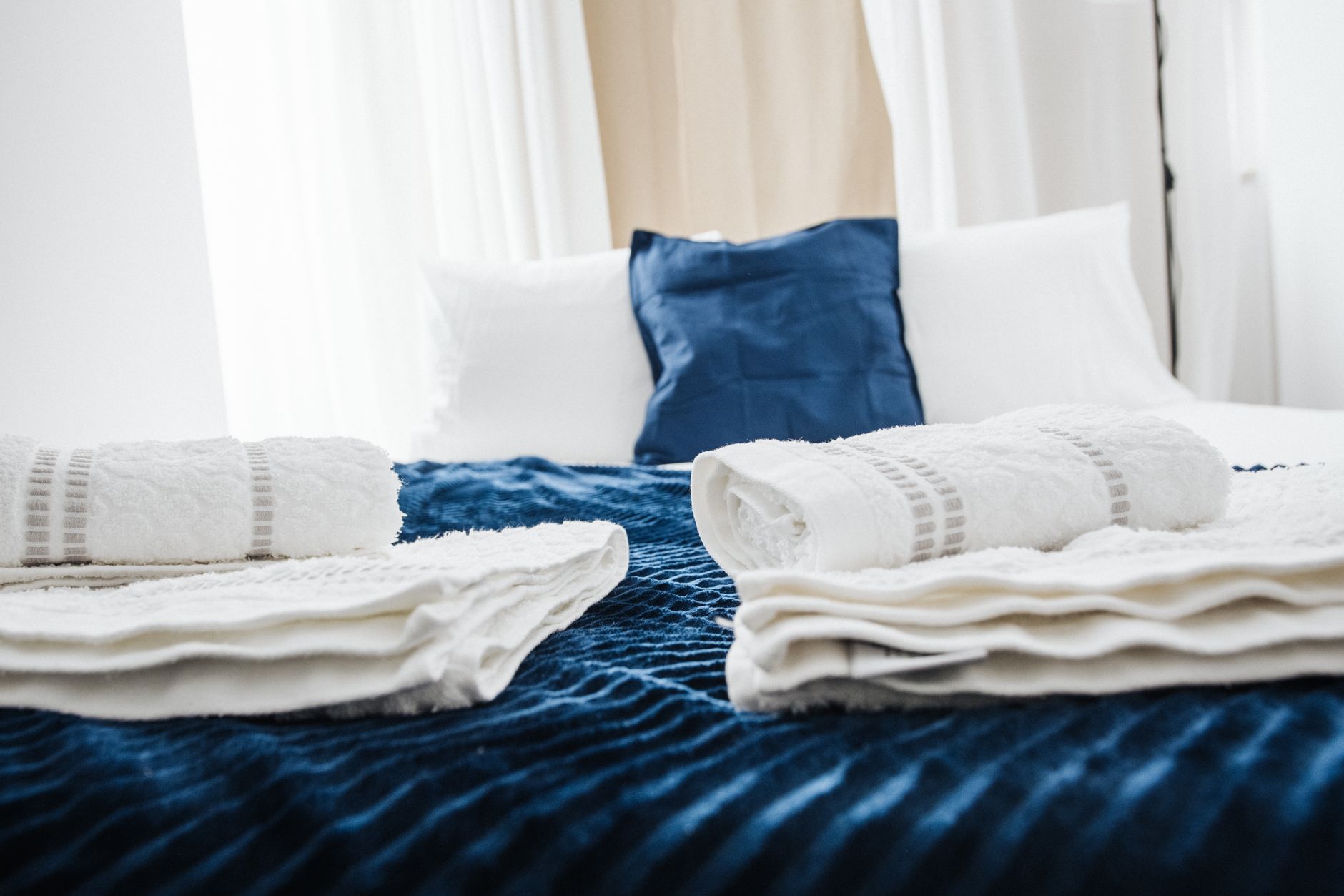A neatly made bed with folded towels beside a notebook and pen