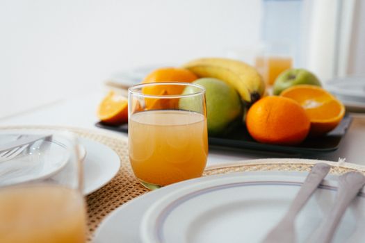 Bright and fresh breakfast setup featuring orange juice and a variety of fruits on a neatly arranged table.