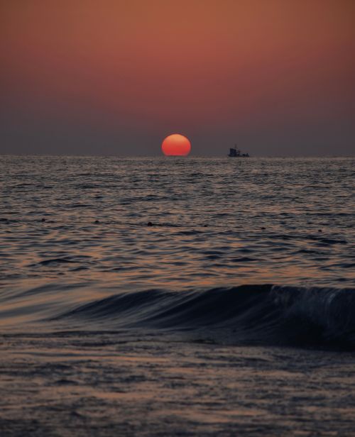 Free Tranquil sunset over the ocean with a vibrant sky and gentle waves. Stock Photo