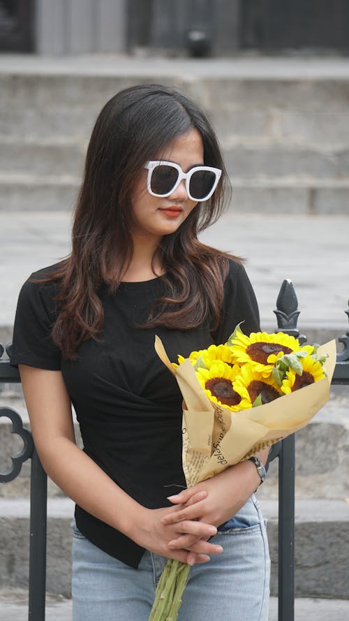 Woman in Black T-Shirt with Bouquet of Sunflowers in Hands
