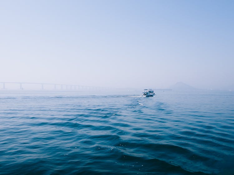 Luxury Yacht Sailing On Foggy Sea By Bridge