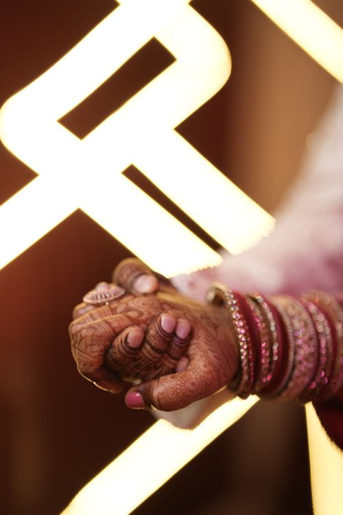 Free Detailed shot of hands adorned with henna and bangles, set against a bright, warm background, emphasizing cultural beauty. Stock Photo