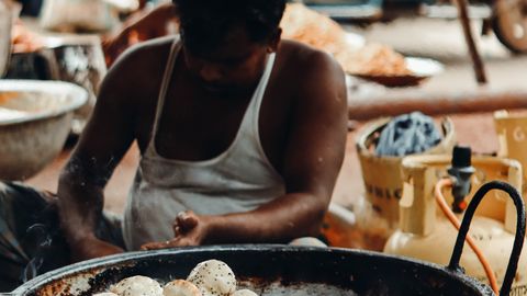 A man prepares traditional street food in Gazipur, capturing the essence of vibrant city life.
