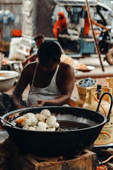 A man prepares traditional street food in Gazipur, capturing the essence of vibrant city life.