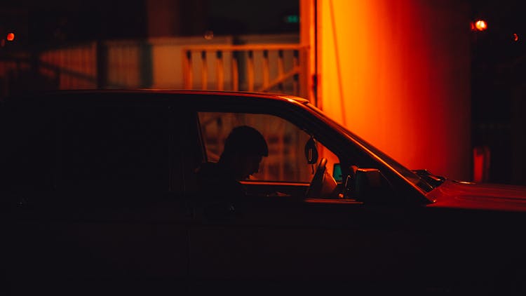 Young Man Sitting In A Car On A Night Street