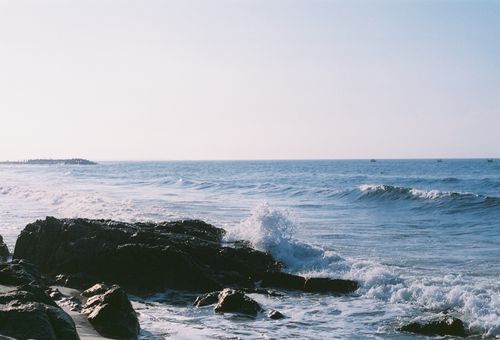 Free Peaceful morning view of waves crashing on a rocky beach during sunrise. Stock Photo