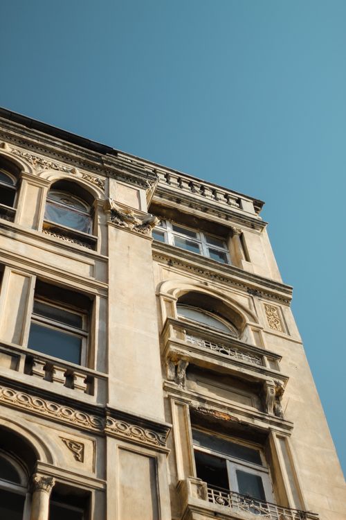 Free Low angle shot of a historical building facade with intricate carvings against a clear blue sky. Stock Photo