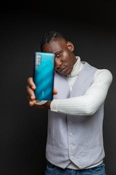 Elegant portrait of a man posing with a smartphone in an indoor studio setting.
