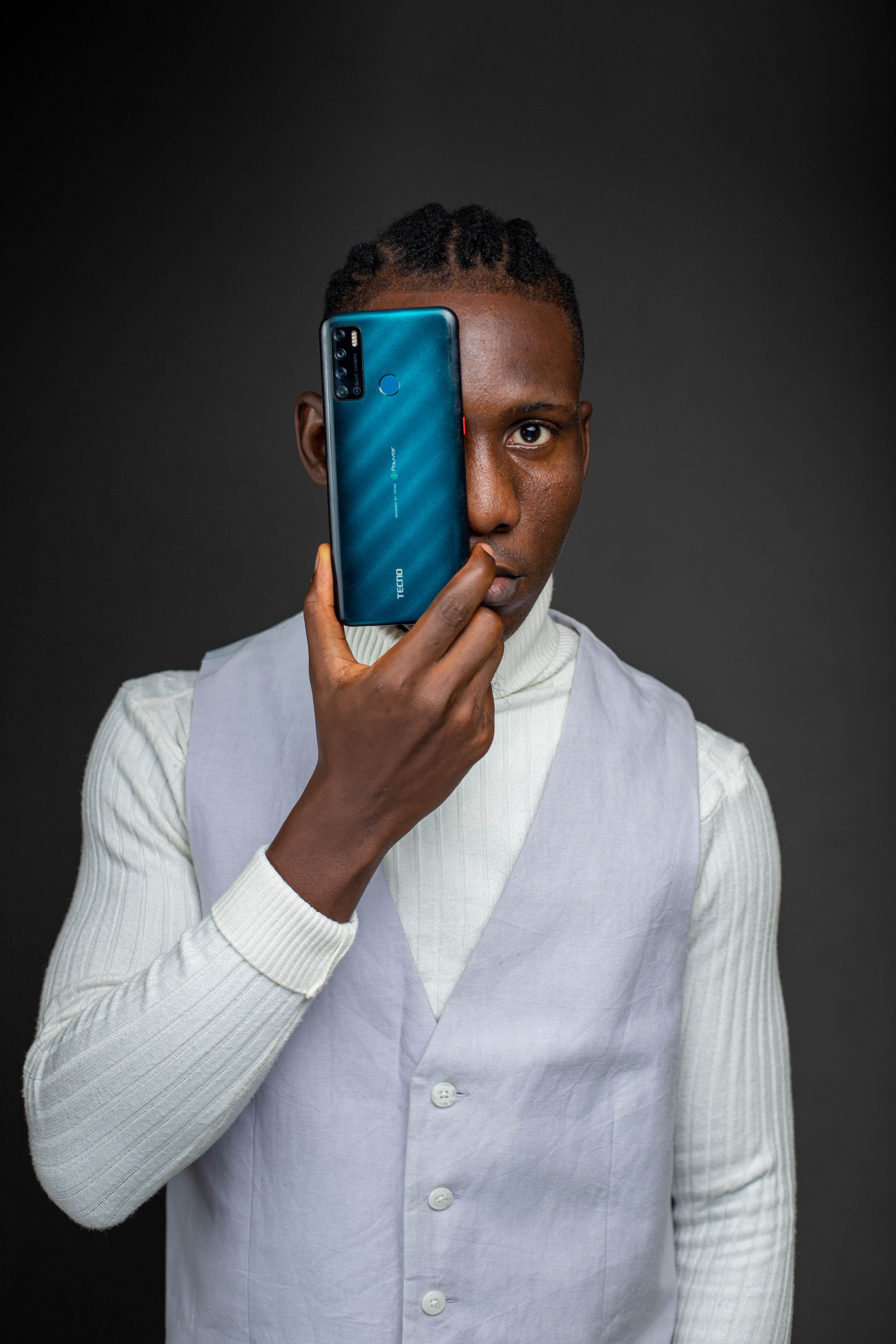 Young man with phone, modern fashion look, studio portrait on black background.