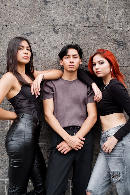 Young Women and Man Posing Together Against Concrete Wall