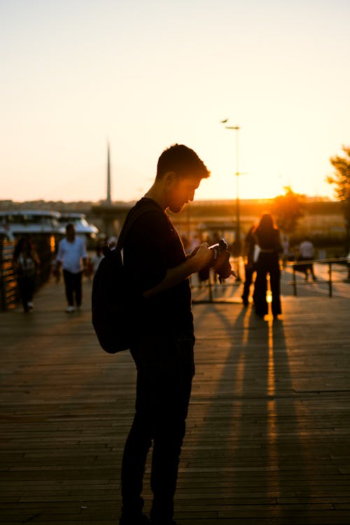 Young Man on a Pier in the Sunset Holding a Camera