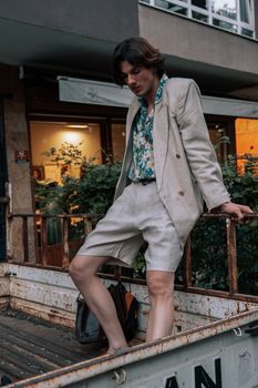 Fashionable young man standing stylishly in urban street, wearing linen blazer and shorts.