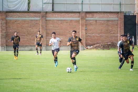 Energetic soccer match in Texcoco, Mexico with players in vibrant sportswear.