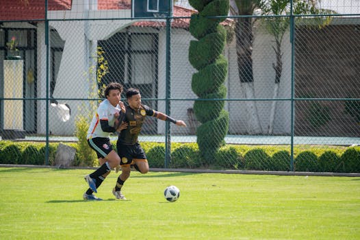 Two athletes compete fiercely in a soccer match on a sunny day in Texcoco, Mexico.