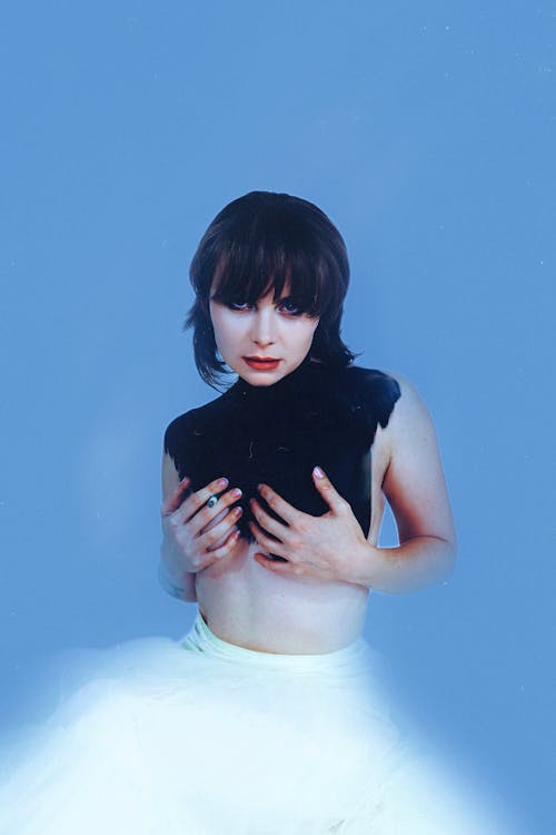 Woman Posing in a White Skirt Against a Blue Background