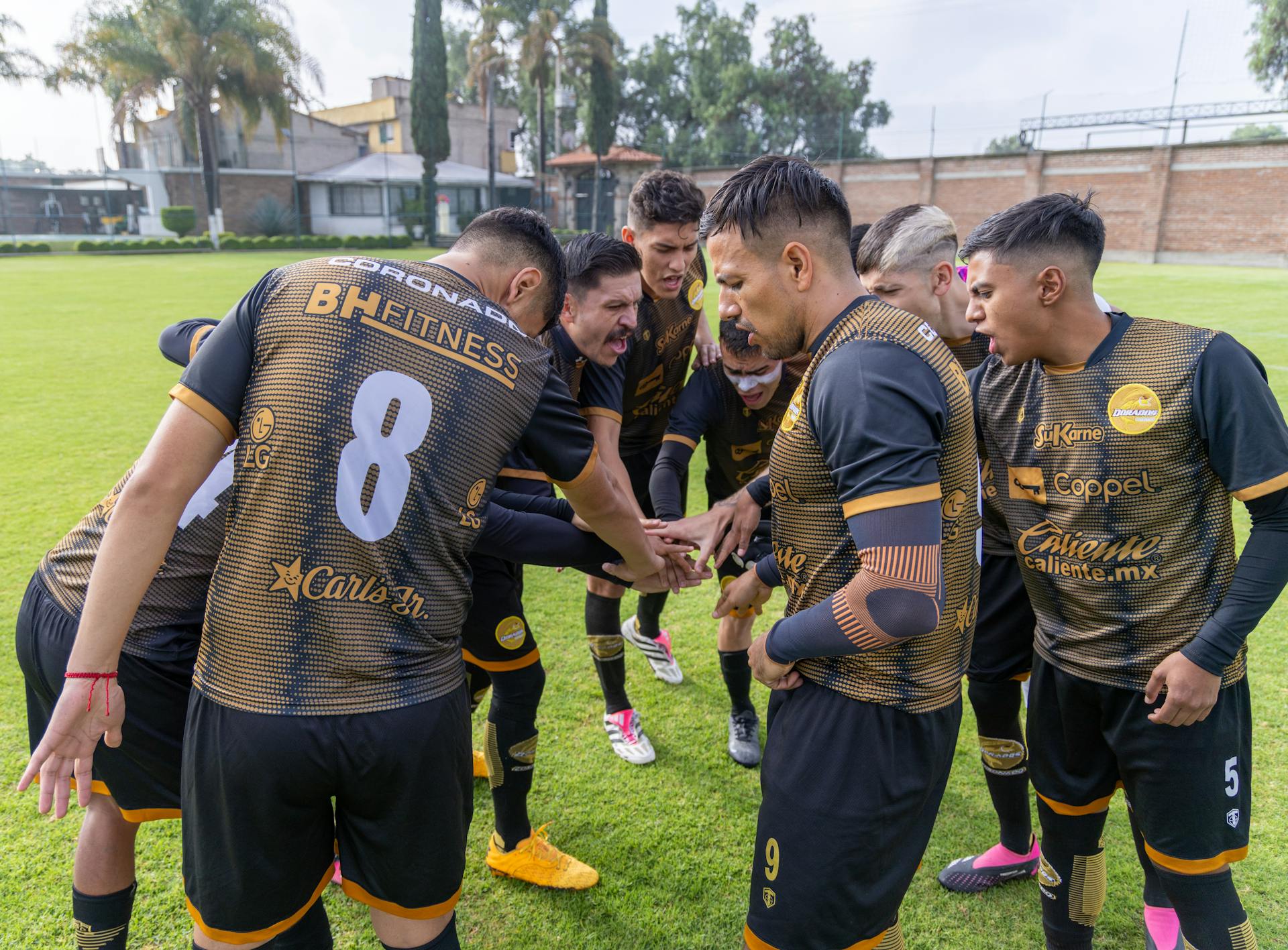 Soccer players in a team huddle on a sunny day at Texcoco, México, displaying unity and teamwork.