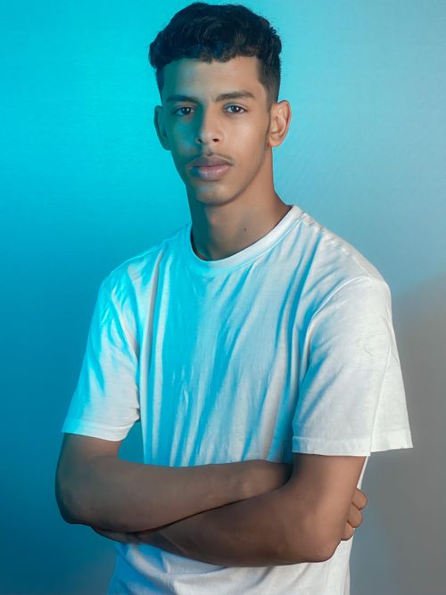 Free Studio portrait of a confident young man with blue lighting effect wearing a white t-shirt. Stock Photo