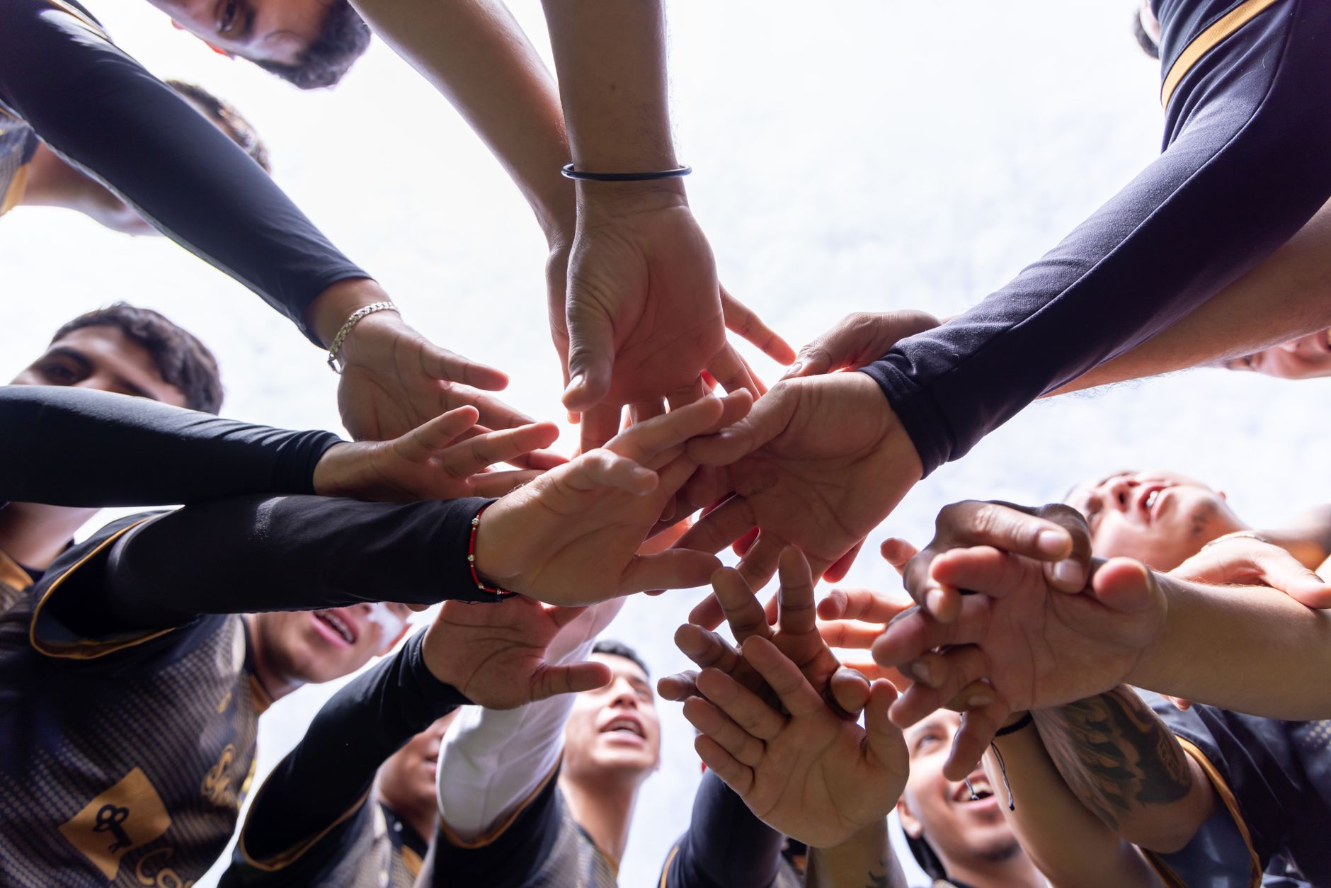 A diverse group of athletes join hands in a team huddle, symbolizing unity and motivation.