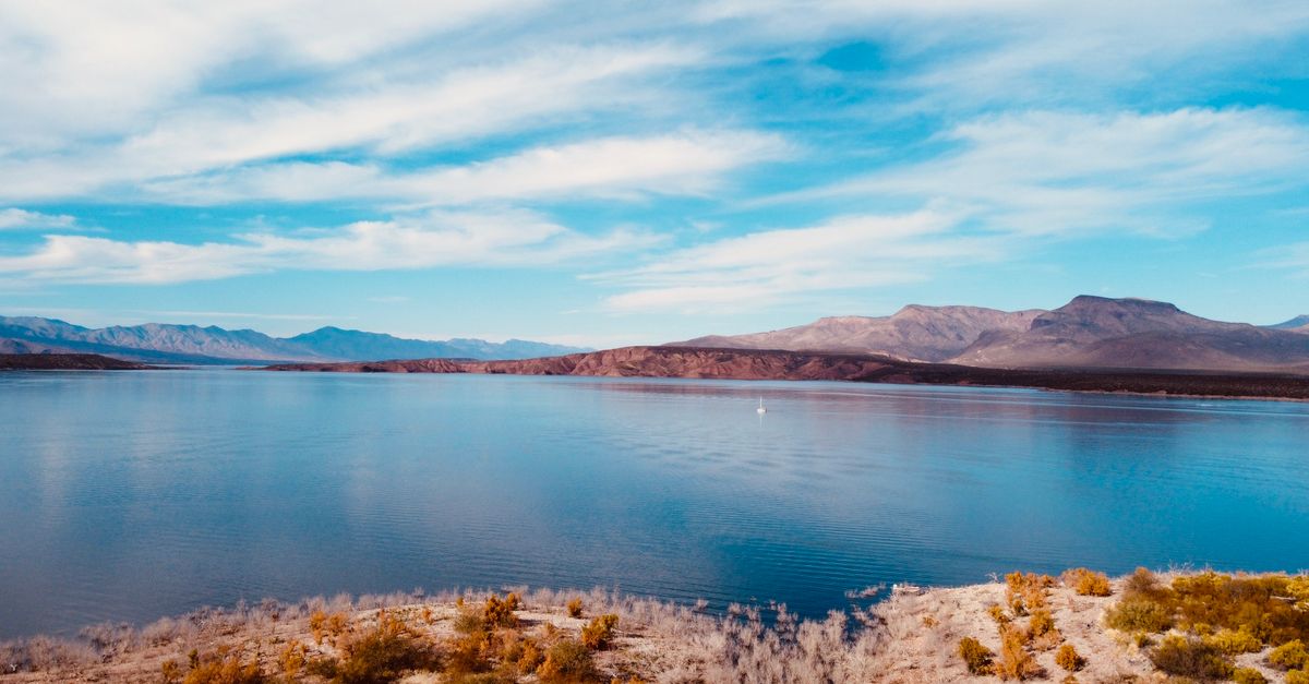 Peaceful panorama of Roosevelt Lake with distant mountains beneath a bright blue sky.