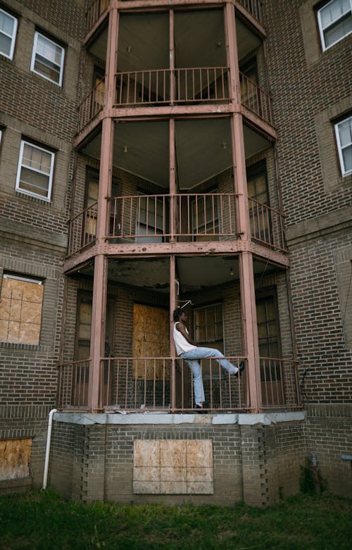 Free A Man Sitting on the Balcony of a Building in City  Stock Photo