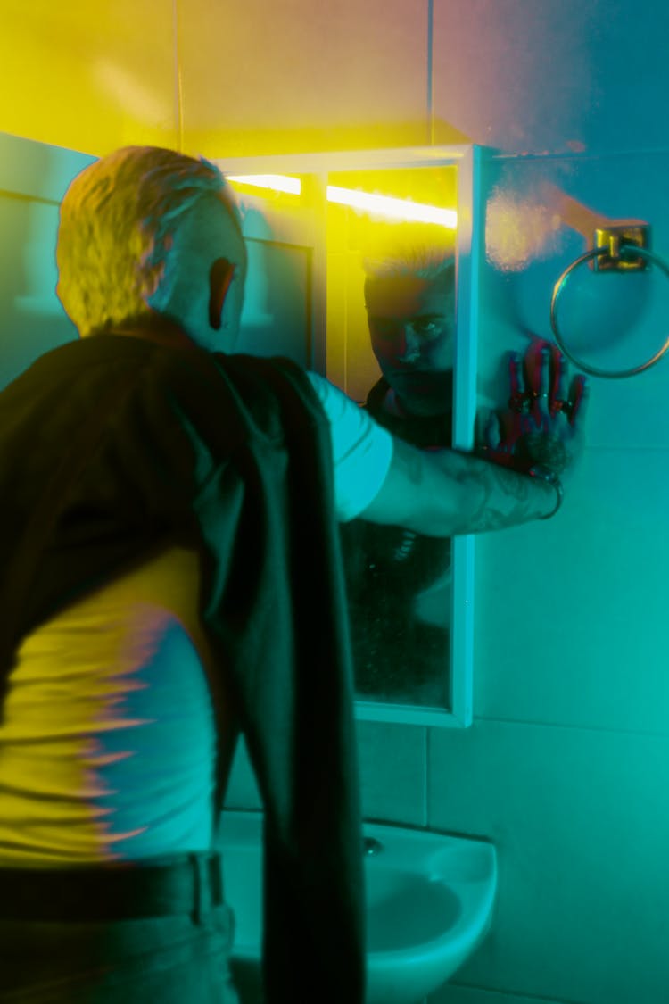 Man Looks At Mirror In Bathroom