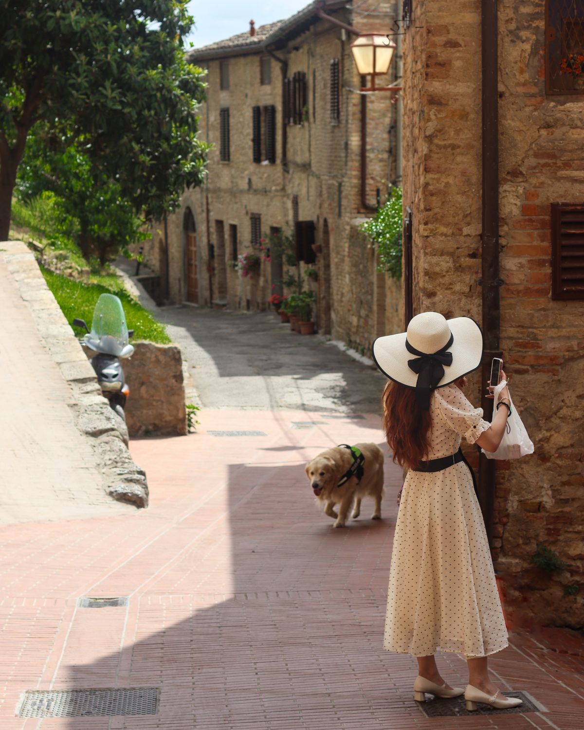 An elegant woman in a sundress and sun hat on an Italian street