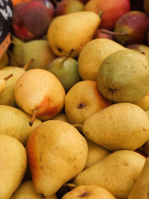 Free A vibrant selection of ripe pears stacked in a market. Ideal for food and nutrition themes. Stock Photo