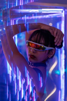 A woman in futuristic sunglasses posing dramatically in neon lights.