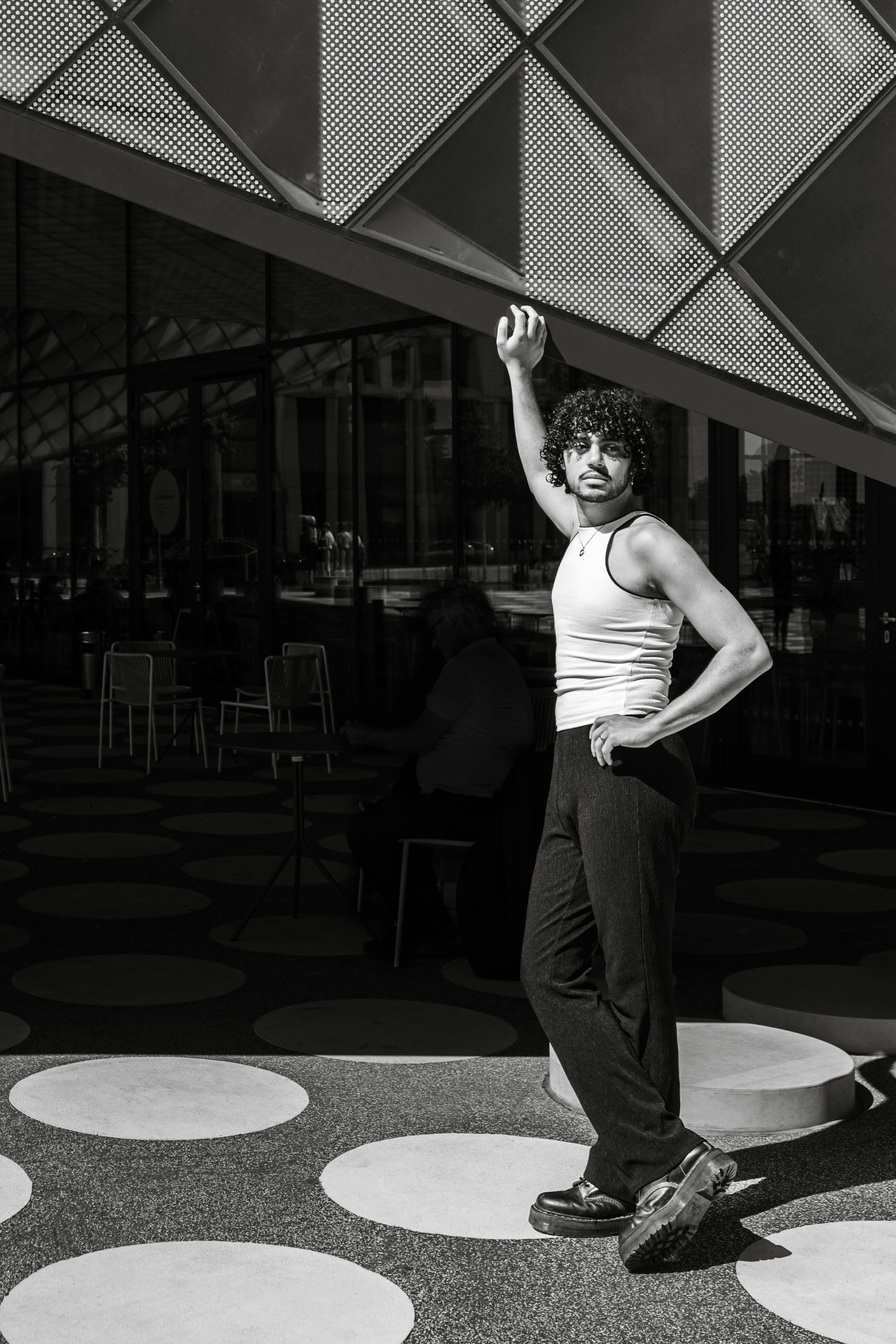 Young man poses fashionably in a modern architectural setting in Berlin, Germany.