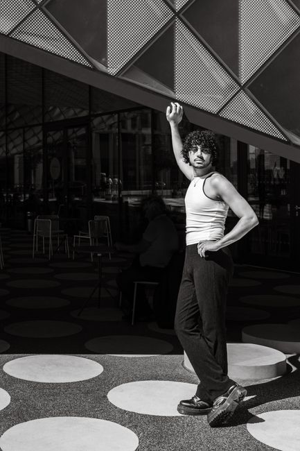 Young man poses fashionably in a modern architectural setting in Berlin, Germany.