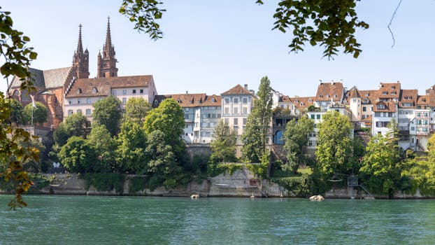 Charming view of Basel's historic buildings and lush greenery along the scenic Rhine River.